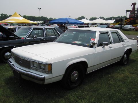 1991 Ford LTD Crown Victoria - White 1980s Ford sedan with chrome trim and black wheels at an outdoor event.