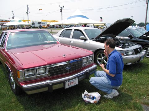 1991 Ford LTD Crown Victoria - A red 1980s Ford Crown Victoria is parked next to a silver Mercury Grand Marquis with its hood open.