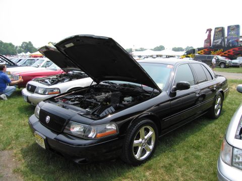 1991 Ford LTD Crown Victoria - A black sedan with its hood open is displayed at an outdoor car show.