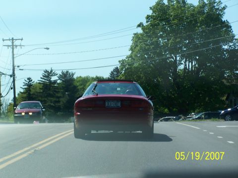 1996 Ford Probe - Rear view of a 1996 Ford Probe driving on a sunny day, with another car visible ahead.