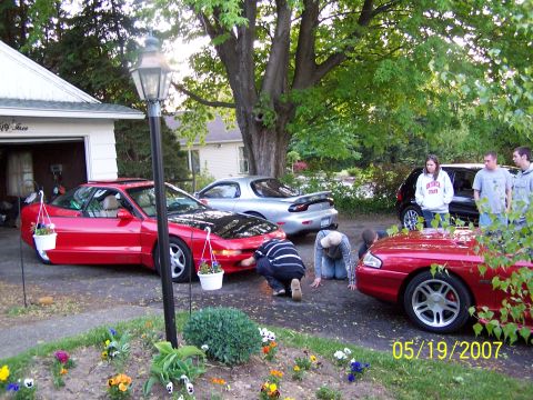 1996 Ford Probe - Group gathered around a red 1996 Ford Probe with its hood open, alongside other vehicles.