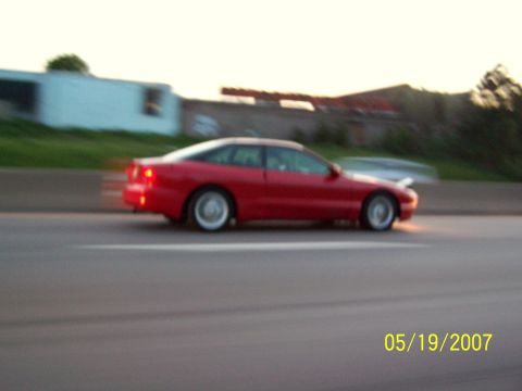 1996 Ford Probe - A red coupe is captured in motion on a highway during the day.