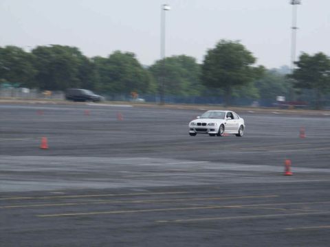 2001 Mercury Grand Marquis - A white sedan navigates a cone course in a large, empty parking lot.