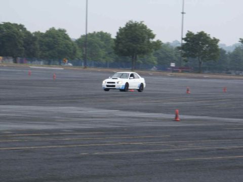 2001 Mercury Grand Marquis - White Subaru WRX STI navigates a wet course marked by orange cones.