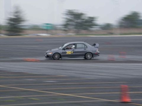 2001 Mercury Grand Marquis - A gray sedan with a spoiler and racing number 310 is seen on a race track, with motion blur indicating speed.
