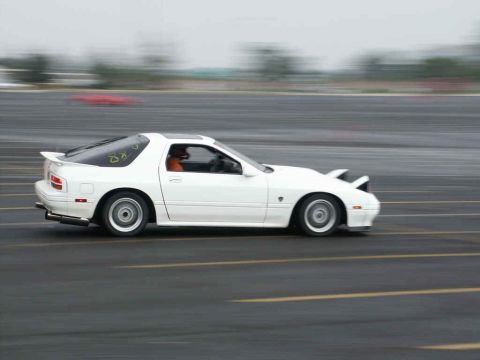 2001 Mercury Grand Marquis - A white Mazda RX-7 is captured in motion on a track, its side profile blurred by speed.