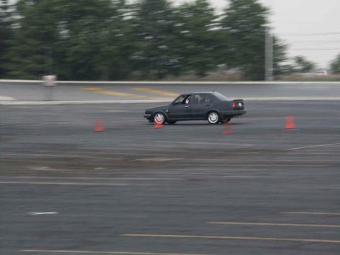 2001 Mercury Grand Marquis - A dark sedan navigates an autocross course with orange cones marking the path.