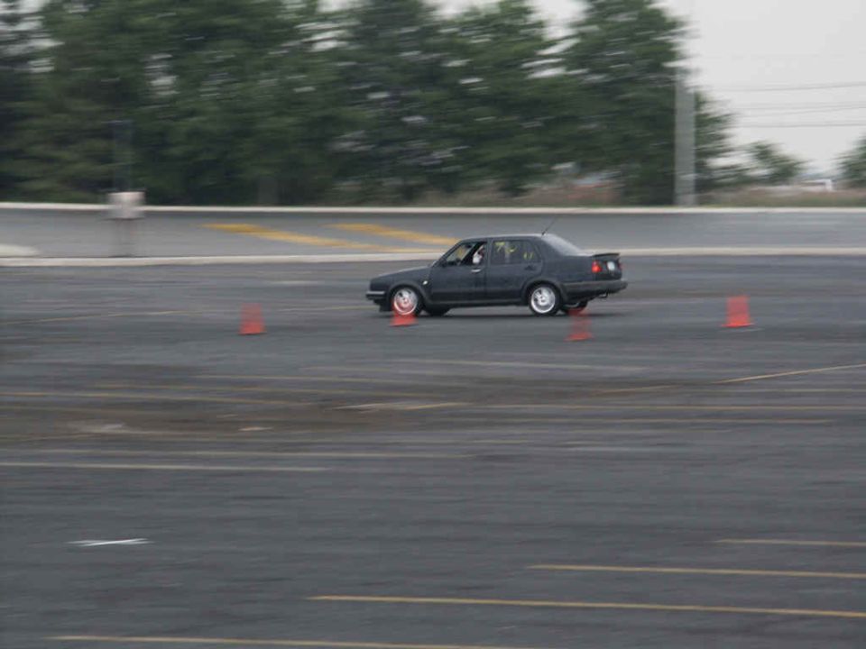 Dark sedan driving on asphalt with orange cones