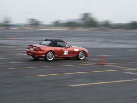 2001 Mercury Grand Marquis - A convertible sports car with a racing number drives on a paved track with blurred background.