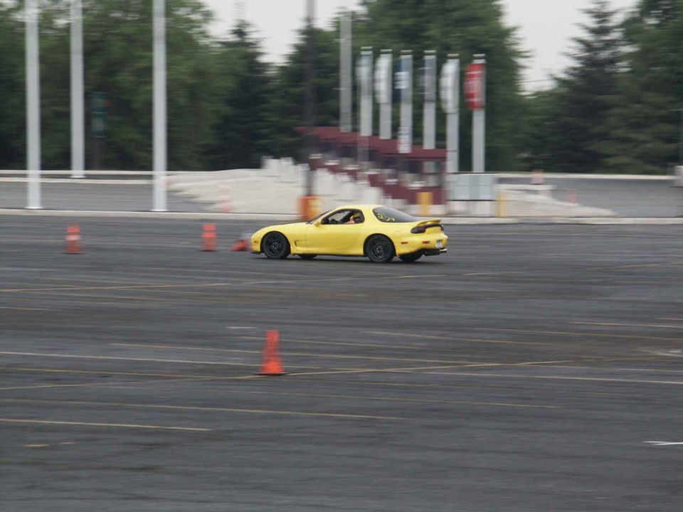 Yellow sports car with a spoiler on a track, viewed from the rear three-quarter angle