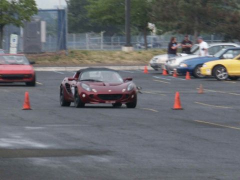 2001 Mercury Grand Marquis - A red convertible sports car navigates a course marked by orange cones, with other vehicles visible in the background.