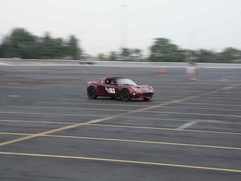 2001 Mercury Grand Marquis - A red sports car with racing numbers navigates a track, possibly during an event.