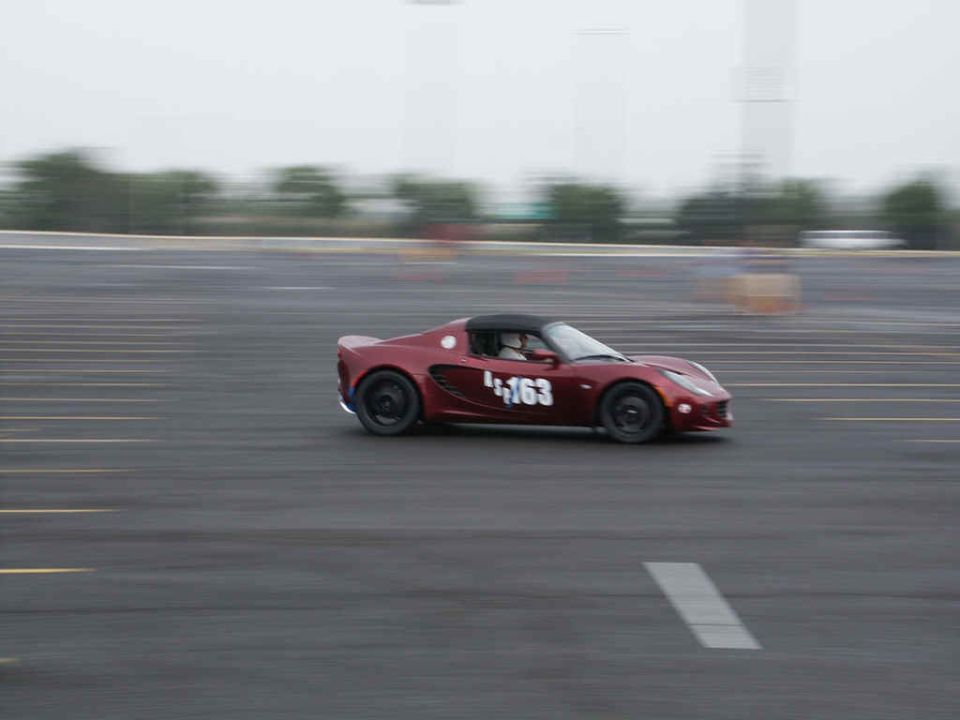 Red sports car with number 163 on the door, driving on a track