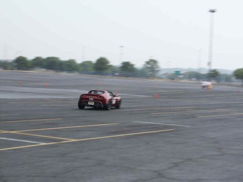 2001 Mercury Grand Marquis - A red sports car navigates a course marked by orange cones in an open lot.