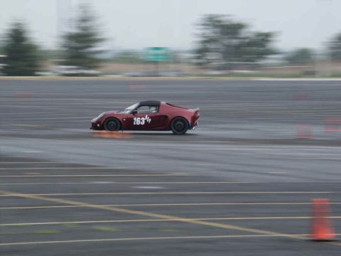2001 Mercury Grand Marquis - Sports car with racing number 163 navigates a wet track during an event.