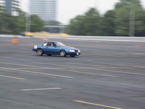 2001 Mercury Grand Marquis - A blue 1987 Ford Mustang races on a track, with the number 45 visible on its side.