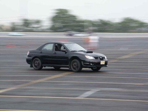 2001 Mercury Grand Marquis - Black Subaru Impreza WRX sedan with hood scoop on a track during an event.