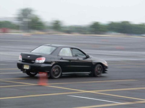 2001 Mercury Grand Marquis - A black sedan navigates a course marked with cones, with motion blur indicating speed.