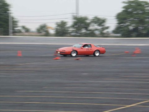 2001 Mercury Grand Marquis - A red sports car navigates a course marked by orange cones on a paved surface.