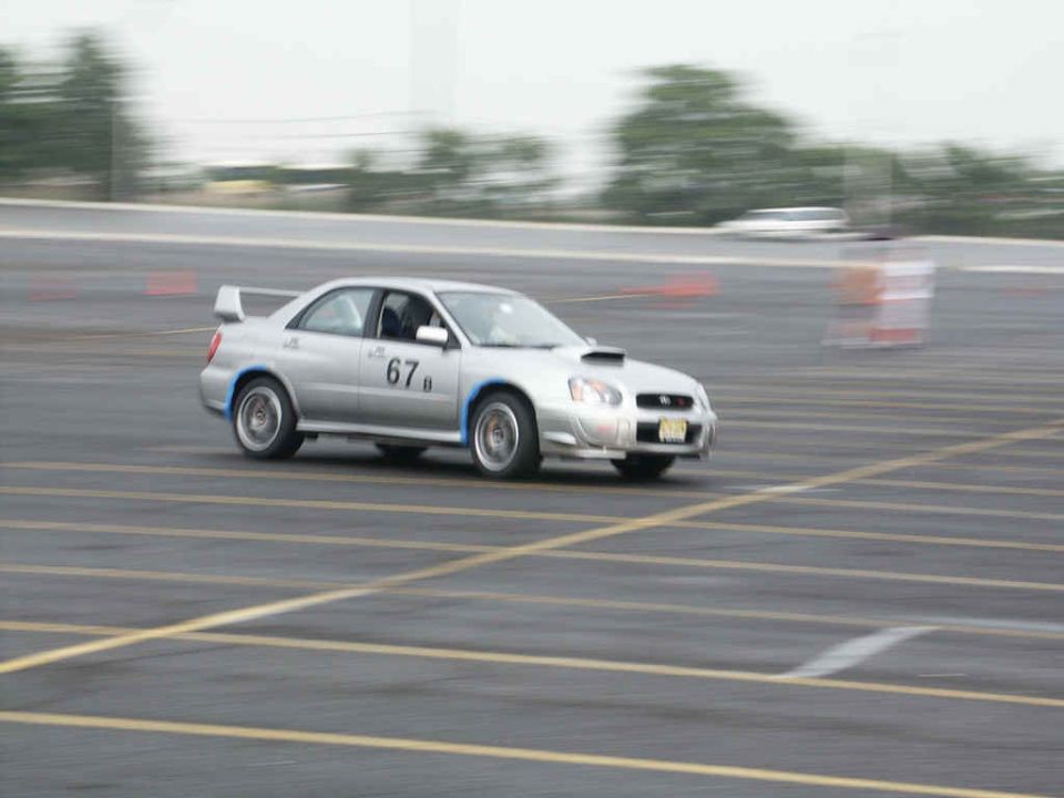Silver Subaru WRX STI with racing number 67b on door, driving on asphalt track