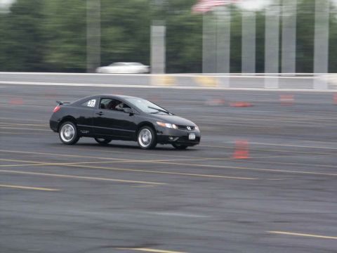 2001 Mercury Grand Marquis - A black coupe navigates a course marked by orange cones, with a blurred white vehicle in the distance.
