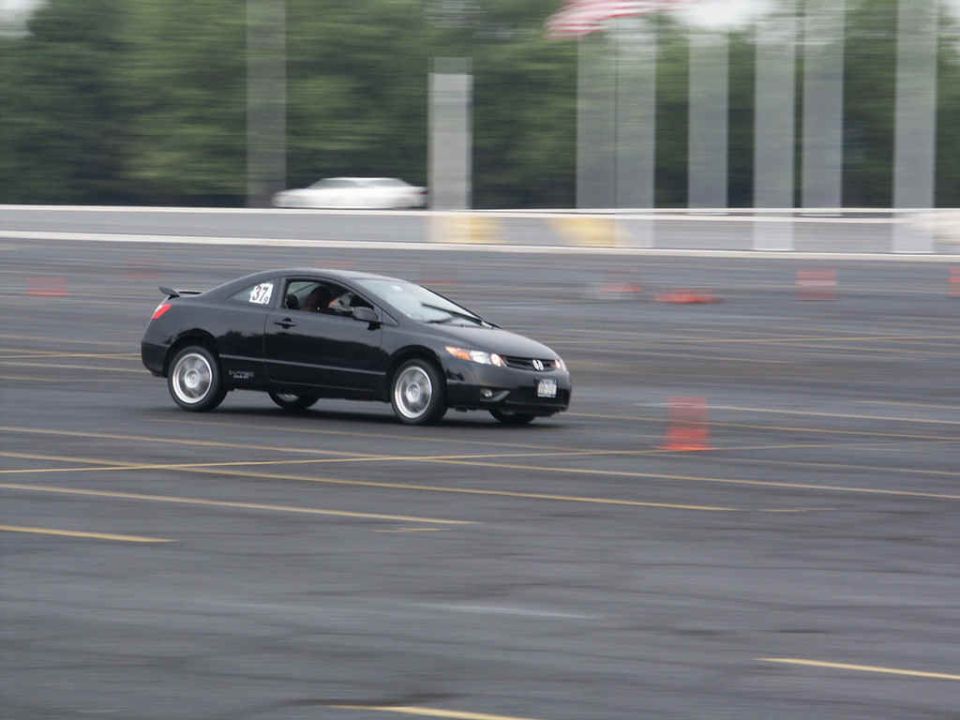 Black coupe with racing number 37 on track, another white car blurred in background