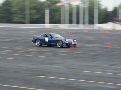 2001 Mercury Grand Marquis - Blue Mazda RX-7 navigates a course marked by orange cones on a paved track.