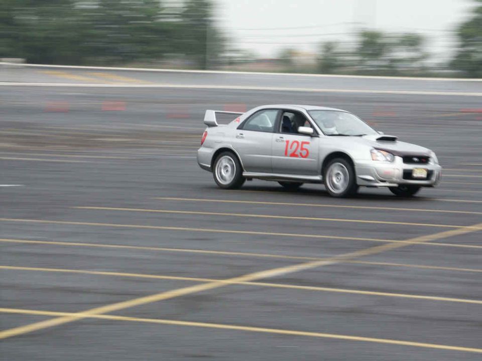 Silver Subaru WRX STI with number 125 on the door, driving on a track