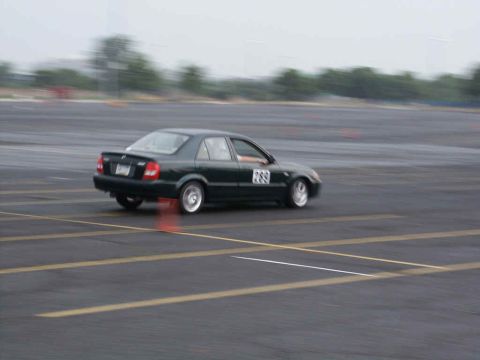 2001 Mercury Grand Marquis - A dark green sedan with racing numbers navigates a track, blurred by motion.