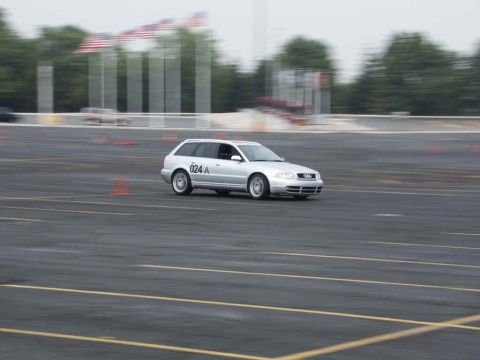 2001 Mercury Grand Marquis - Silver Audi wagon navigates a race track with blurred flags and trees in the background.