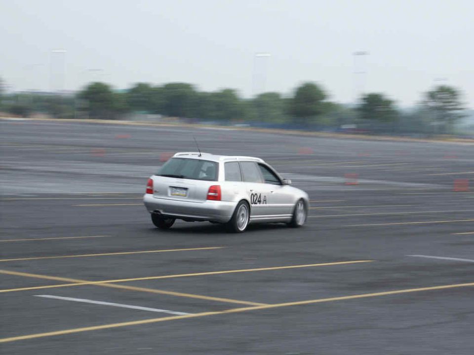 Silver station wagon with number 024 A on the door, driving on a paved track with orange cones