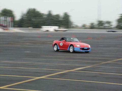 2001 Mercury Grand Marquis - A red and blue sports car navigates a track, indicated by orange cones and painted lines.