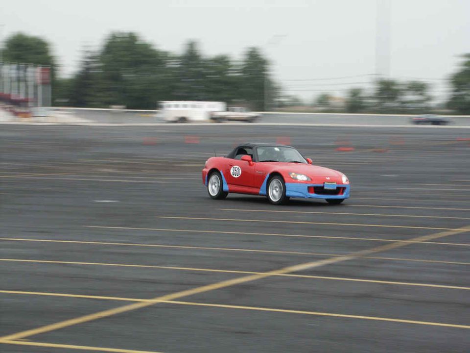 red sports car with blue front bumper and number 50 on door, driving on a track