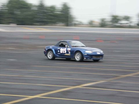 2001 Mercury Grand Marquis - A blue convertible sports car, identified by the number 815 on its door, navigates a race track.