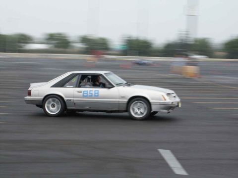 2001 Mercury Grand Marquis - A silver 1987 Ford Mustang GT coupe with racing number 858 on its door is captured in motion on a track.