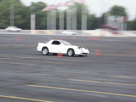2001 Mercury Grand Marquis - A white sports car navigates a course marked by orange cones, with other vehicles blurred in the background.