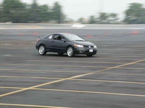 2001 Mercury Grand Marquis - A black sedan navigates a race track, indicated by orange cones and yellow lane markings.