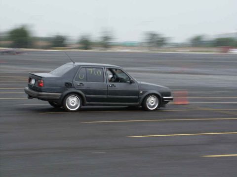 2001 Mercury Grand Marquis - A dark sedan with racing numbers 'U 710' is captured in motion on a paved track, likely during a motorsports event.
