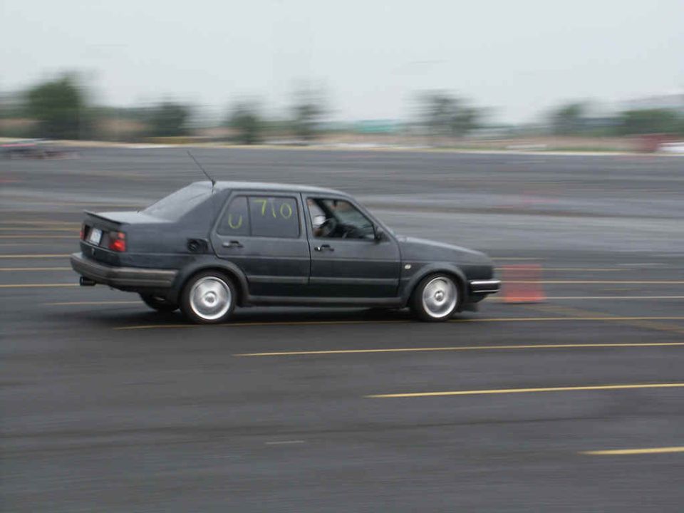 Dark sedan with racing numbers 'U 710' on side, in motion on a track