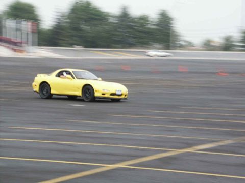 2001 Mercury Grand Marquis - A yellow sports car navigates a track with orange cones, while another car is visible in the distance.