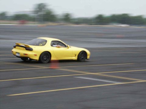 2001 Mercury Grand Marquis - Yellow Mazda RX-7 captured in motion on a race track during an event.