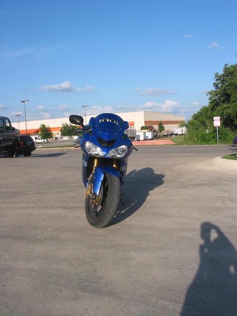 1996 Ford Bronco - A blue motorcycle is parked on a concrete surface under a partly cloudy sky.