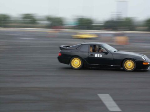 2001 Mercury Grand Marquis - Black sports car with yellow wheels on a track, another car visible in the distance.