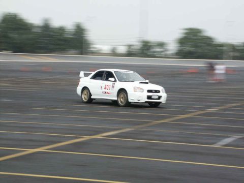 2001 Mercury Grand Marquis - A white Subaru WRX is seen on a race track with orange cones marking the course.