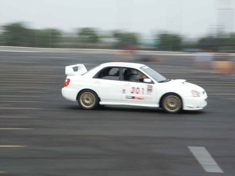 2001 Mercury Grand Marquis - A white Subaru Impreza WRX STI, identified by its distinctive body style and racing decals, navigates a track with motion blur.