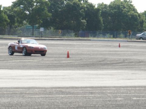 2001 Mercury Grand Marquis - A red convertible navigates a course marked by orange cones on a paved lot.
