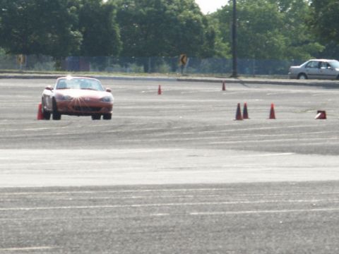 2001 Mercury Grand Marquis - A red convertible navigates a course marked by orange traffic cones on a sunny day.