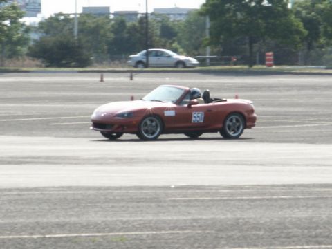 2001 Mercury Grand Marquis - A red convertible sports car with racing number 551 navigates a track during an event.