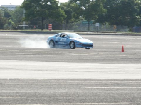 2001 Mercury Grand Marquis - A blue sports car is seen drifting on an asphalt surface, kicking up dust.
