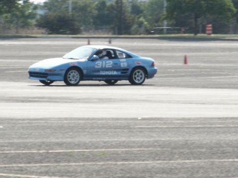 2001 Mercury Grand Marquis - A blue Toyota MR2 is seen on a track with orange cones in the background.